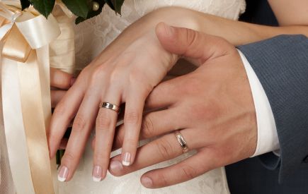 Hand einer Frau und eines Mannes bei der Hochzeit mit Hochzeitsringen